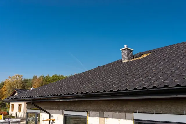 Pannendak van een woning — Overzicht van een woning met een donker pannendak, nok en schoorsteen.